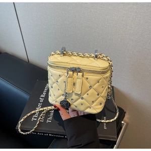 Dettaglio mini borsa gialla trapuntata con strass e ciondolo a forma di camelia nera