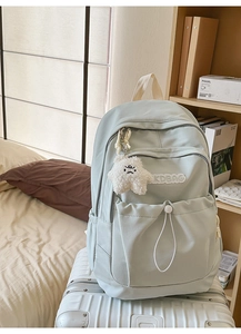 Detail of light green nylon backpack with star charm and drawstring pocket on luggage