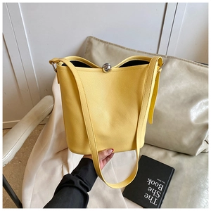 Détail du sac seau jaune en cuir grainé avec fermeture décorative en boule de métal argenté