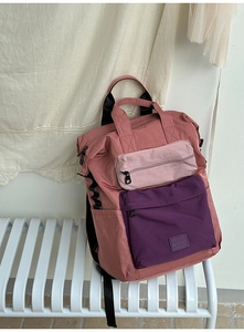 Detail of color-block pink backpack with multi-compartments and woven brand label