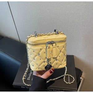Dettaglio della mini borsa gialla trapuntata con strass e ciondolo a camelia