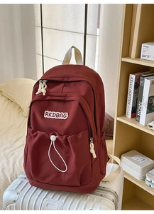 Detail view of red nylon backpack showing RKDBAG embroidery and drawstring pocket
