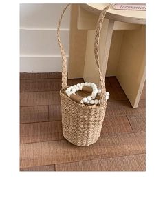 Détails du sac seau en paille tressé avec des poignées en perles blanches et doublure brune