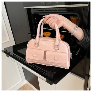 Close-up of pink glossy pillow bag featuring double front pockets and silver hardware detail