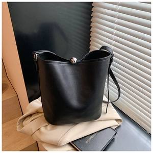 Gros plan sur le sac seau en cuir noir avec boucle boule argentée sur un vêtement