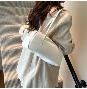 Close-up of minimalist white cloud shoulder bag showing soft texture and long strap details