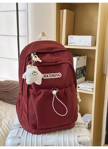 Detail of burgundy nylon backpack featuring adjustable drawstrings and plush star pendant