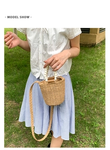 Détail du sac seau en paille tissée avec anse en perles blanches et bandoulière
