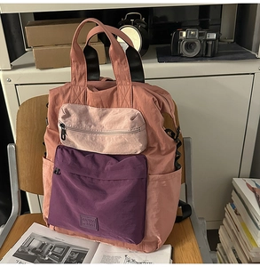Detail of multi-pocket nylon backpack with contrast colors and dual carry handles