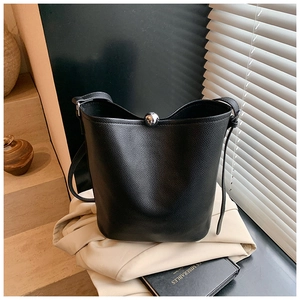 Détail du sac seau en cuir grainé noir avec boucle en perles argentées sous lumière naturelle