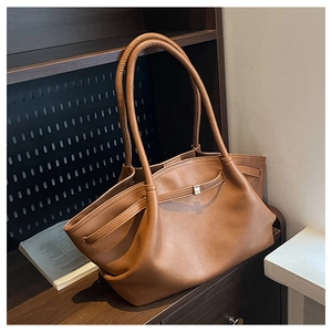 Detail of brown faux leather tote bag with silver metal buckle and side wing design