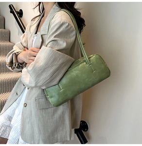 Close-up of a grass green rectangular baguette bag with vintage texture leather on a model