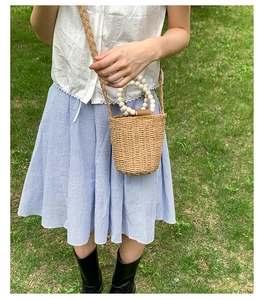 Détail du sac seau en paille avec anse en perles et bandoulière tissée artisanale