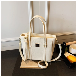 Detail of creamy white bucket bag featuring litchi texture and gold metal accents