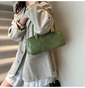 Side view of a vintage green leather shoulder bag worn on a minimalist indoor background