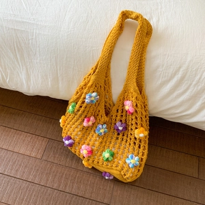 Détail d'un sac cabas en crochet jaune avec fleurs 3D tricotées sur drap blanc