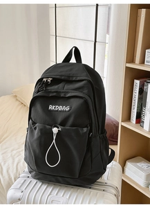 Detail of a black nylon backpack with white drawstring accents on a white suitcase