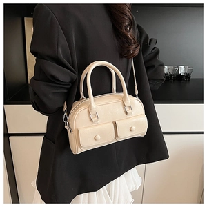 Detail view of cream Boston bag with buckle pockets and cylinder handles for women