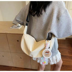 Detail of cream canvas dumpling bag featuring an adjustable strap and cute capybara charm
