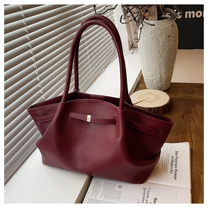 Detail of burgundy tote bag showing soft leather texture and elegant gold buckle accent
