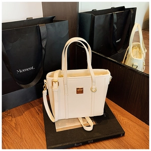 Detail of off-white lychee grain leather bucket bag with gold logo and adjustable strap