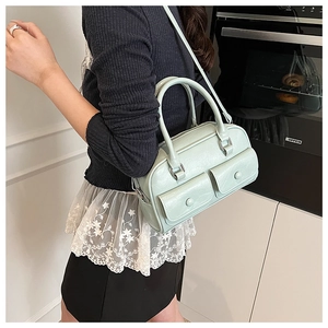 Pale green shoulder bag detail featuring two front flap pockets and adjustable metal D-rings