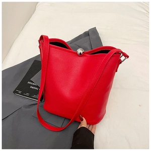 Détail du sac seau en cuir grainé rouge avec fermoir magnétique boule argentée et coutures apparentes