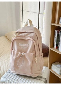 Detailed close-up of pink nylon backpack with RKDBAG patch on a silver suitcase