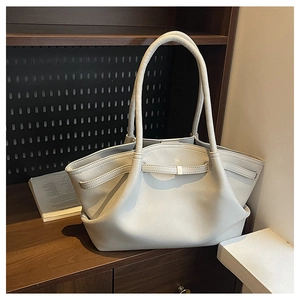 Close-up of light grey tote bag with gold metal buckle on a wooden counter top