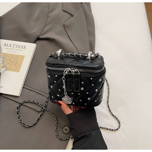 Dettaglio della mini borsa vanity nera trapuntata con strass argentati su un blazer