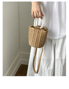 Détail du sac seau en paille tressée avec anse en perles et bandoulière tressée