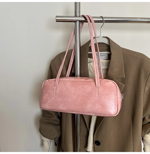 Detailed side view of pink minimalist baguette shoulder bag with slim straps and metal zip