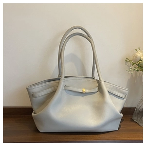 Close-up of beige leather tote bag with unique fold design and gold metal fastener