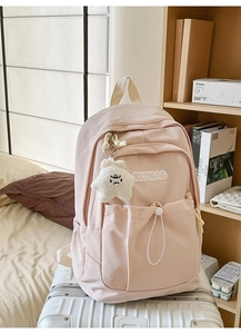 Detail of pink nylon backpack with drawstring pocket and plush star charm accessory