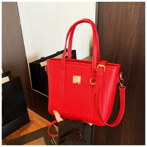 Close-up of red lychee textured bucket bag with golden hardware and square metal plate