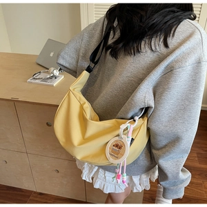 Detail of yellow crescent crossbody bag with cartoon charm shown on model in home setting