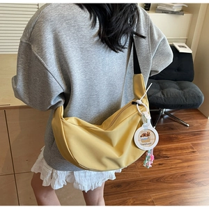Detail of yellow nylon half-moon crossbody bag with cute capybara charm and strap