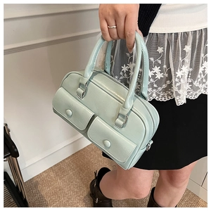 Detail of mint green commuter pillow bag featuring double front buckle pockets and silver hardware