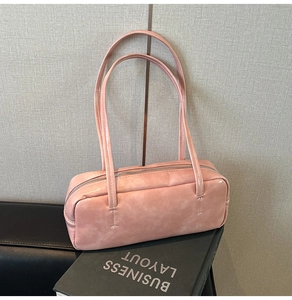 Pink marbled PU leather shoulder bag with top zipper and cross-stitch detail on a book