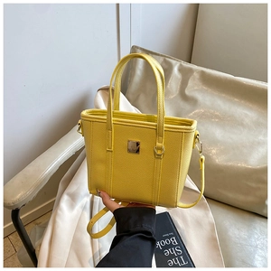 Detail of yellow lychee pattern PU leather bucket bag with golden logo and strap