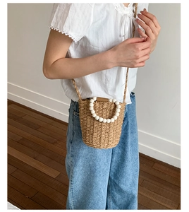 Détail du sac seau en paille tressée à la main avec de grandes poignées en perles