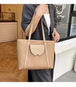 Detail of beige tote bag with a golden metal buckle pocket on a textured leather surface