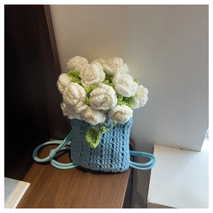 Détail du sac seau au crochet bleu clair avec décorations florales de roses blanches