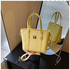 Detail of yellow litchi pattern bucket bag with square metal plate and adjustable strap
