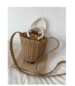 Détail du sac seau en paille avec anses en perles blanches et doublure marron