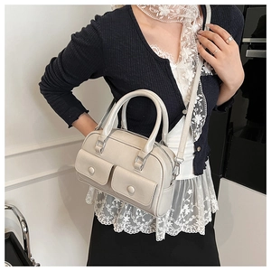 Close-up of light gray boston handbag featuring dual handles and front button pockets