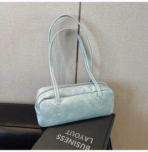 Detail of light blue faux leather baguette bag with dual slim shoulder straps and zipper