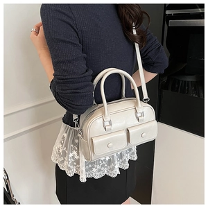 Detail of cream leather boston bag showing front flap pockets and smooth leather texture