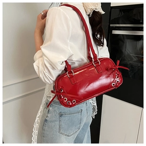 Dettaglio della borsa sottobraccio in vernice rossa con fiocco decorativo e occhielli