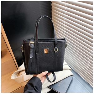 Close-up of black lychee grain faux leather tote bag with gold metal square buckle detail